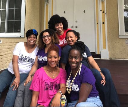 A group of six black women wearing "cite black women" t-shirts in a variety of colours.