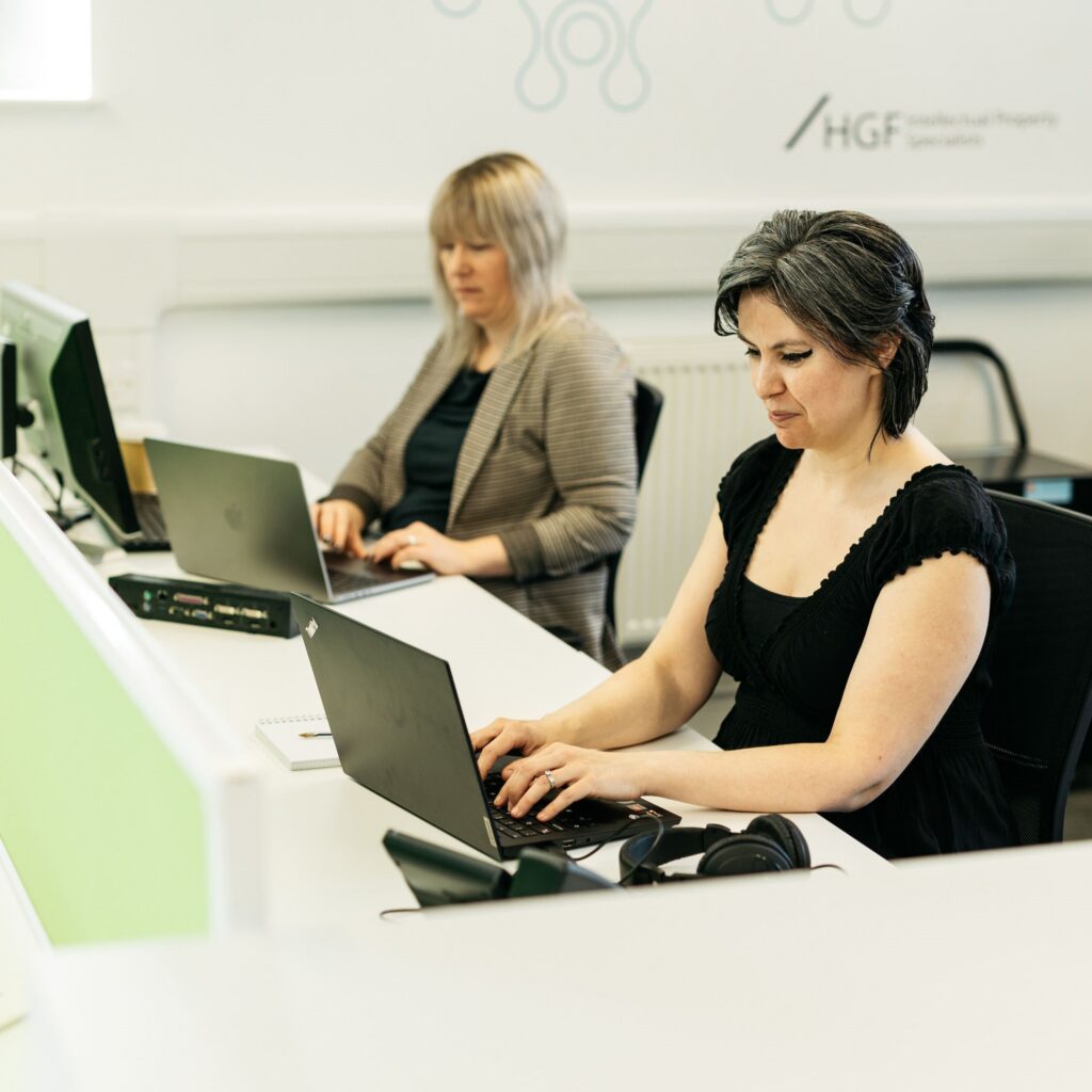 Two women working at a desk on laptops