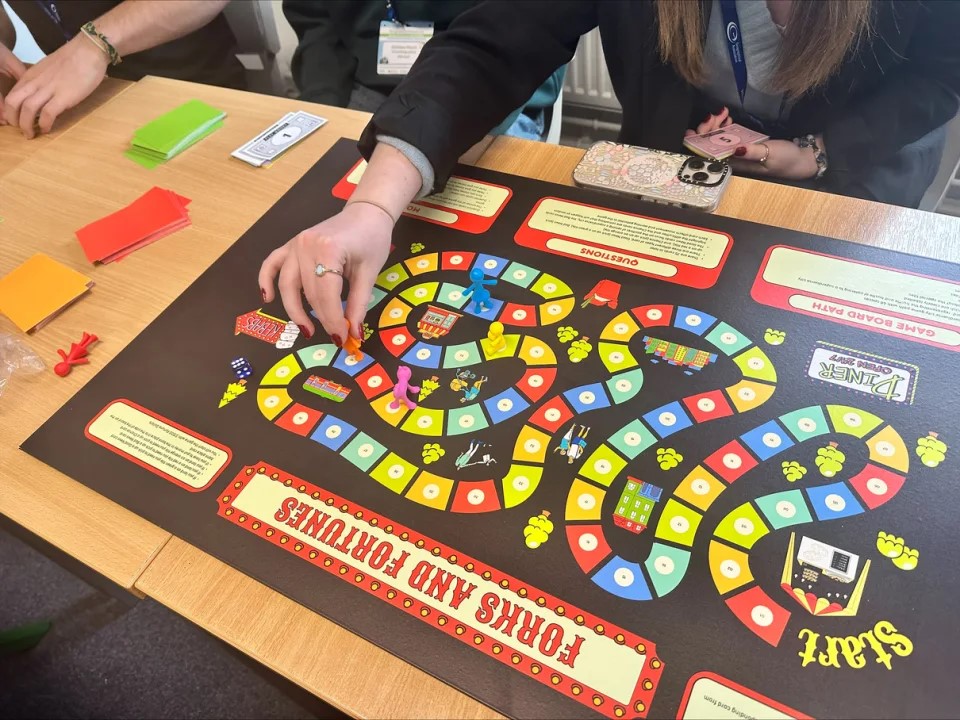 A close-up of someone moving a piece around a board game playing board