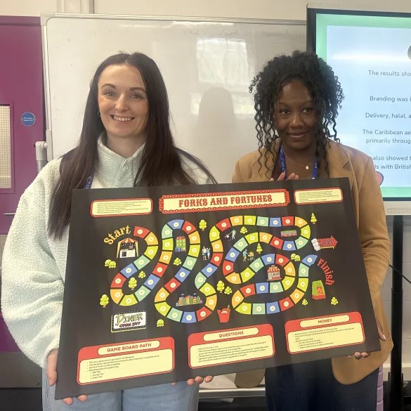 Two women holding the playing board for a board game